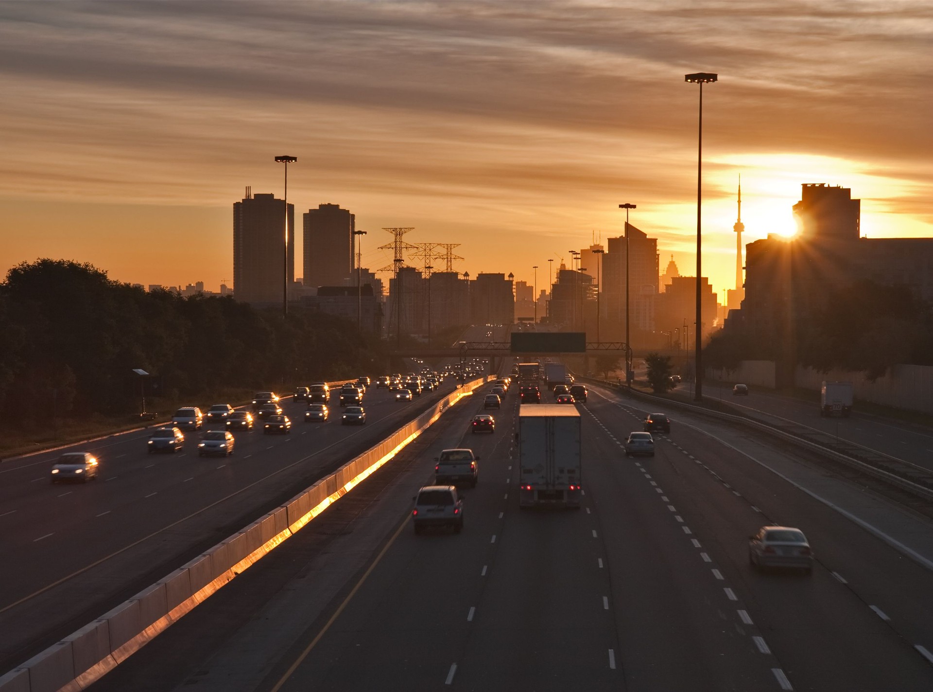 Stream of cars traveling on a busy highway at sunrise